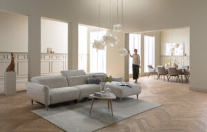 Skagen Studio Birkholm modular sofa in cream fabric, in a bright living room with a person standing beside it.