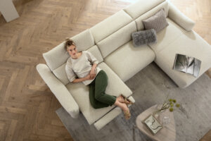 Skagen Studio Birkholm modular sofa in cream fabric, corner configuration with a person, seen from above.