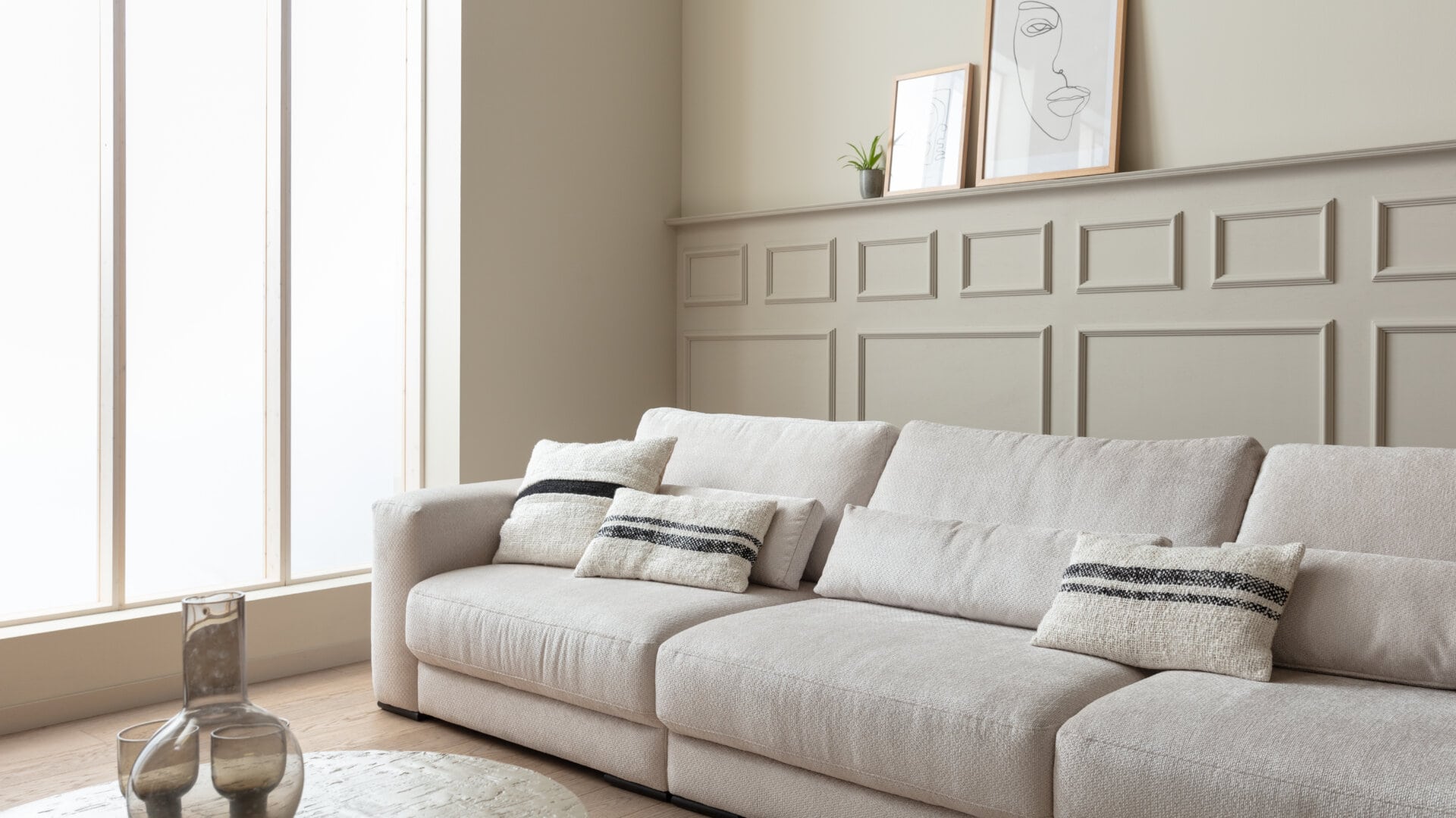 Skagen Studio Egholm modular sofa in cream fabric, seen across the room with decor on the shelf.
