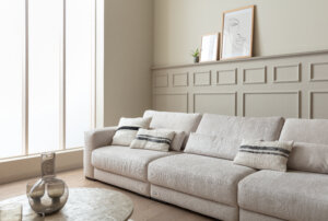 Skagen Studio Egholm modular sofa in cream fabric, seen across the room with decor on the shelf.