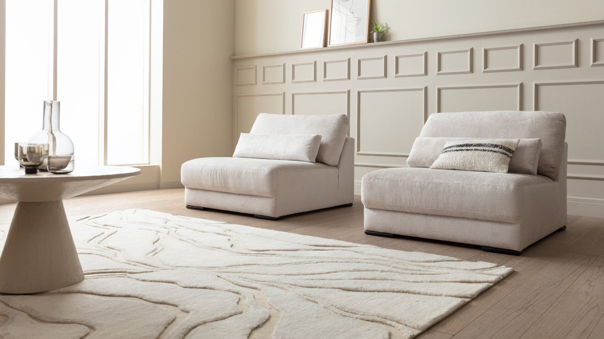 Skagen Studio Egholm modular sofa in cream fabric, with an Armchair and a patterned rug in a bright room.