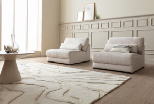 Skagen Studio Egholm modular sofa in cream fabric, with an Armchair and a patterned rug in a bright room.