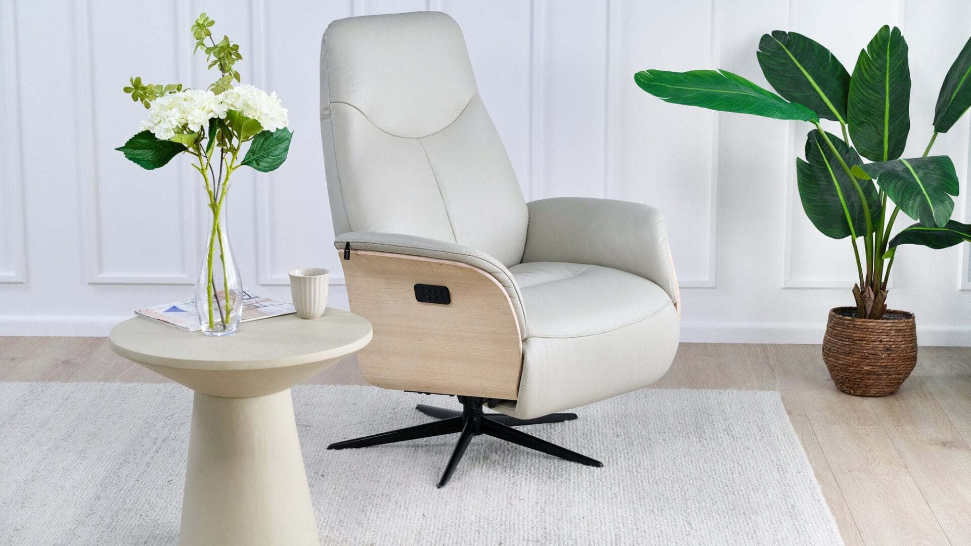 Skagen Studio Hejrede Essential recliner in Madras white leather with a light wood shell and black swivel base, in a styled living room.